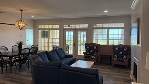 A living room with a sectional sofa, dining table, chairs, and two patterned armchairs.