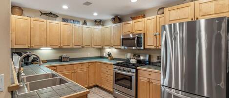 A modern kitchen with wooden cabinets, stainless steel appliances, and a tiled backsplash.