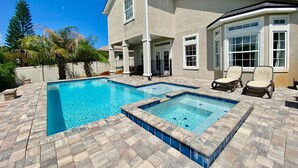 Une maison à deux étages avec une piscine et un jacuzzi.