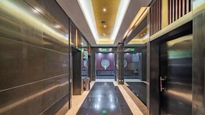 Un couloir d’hôtel moderne avec un sol réfléchissant, des murs sombres et un plafond doté d’un éclairage encastré.
