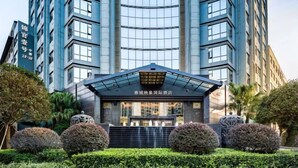 Un hôtel moderne doté d’une entrée imposante, entouré d’un aménagement paysager soigné et d’une grande façade.