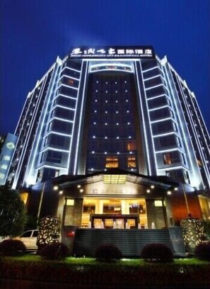 Un hotel de varios pisos con una entrada destacada y señalización iluminada.