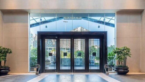 Une entrée moderne avec des portes vitrées et une vue sur les bâtiments environnants.
