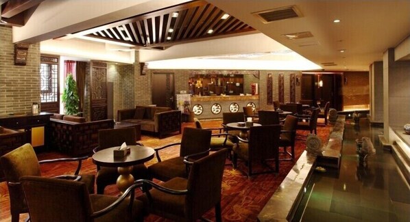 Un vestíbulo amplio con zona de bar, asientos cómodos y una pared decorativa con diseños circulares.