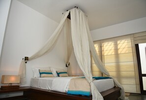 Un dormitorio con cama a dosel, mesita de noche y ventana con persianas.