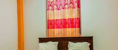 Un dormitorio con una cama, ventilador de techo y ventana con cortina.