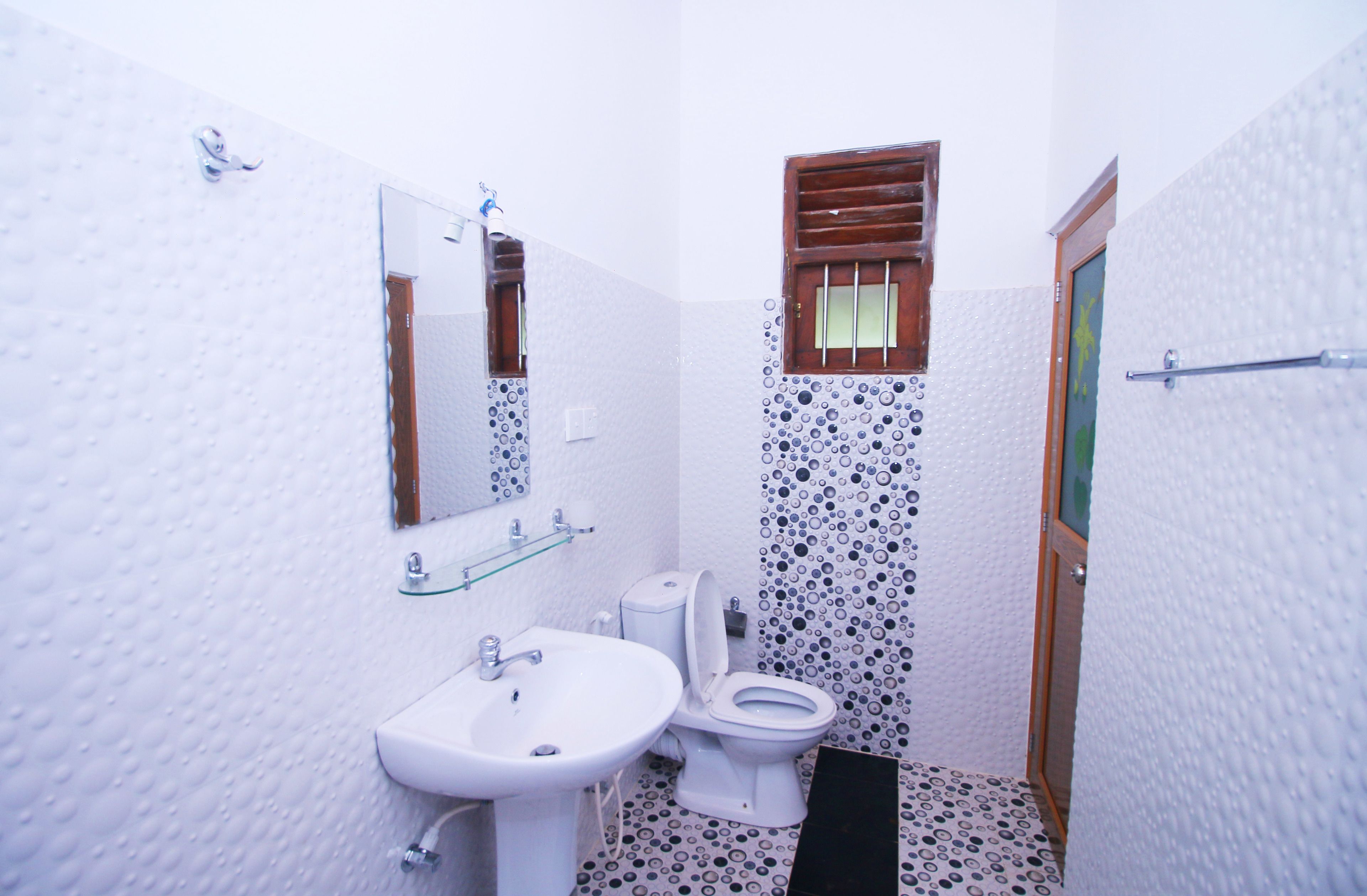 A small bathroom with a white sink, toilet, and mirror.