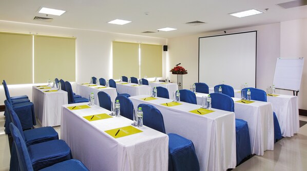 Une salle de conférence équipée de plusieurs tables, de chaises et d’un tableau blanc.