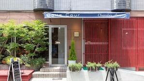 L’entrée d’un restaurant avec une enseigne indiquant « Bene Cour » et « Chambre Asami ».