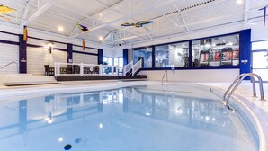 An indoor swimming pool with a clear view of the pool area, including the poolside seating and a staircase leading to the upper level. - West Wing at Park Town (Saskatoon)