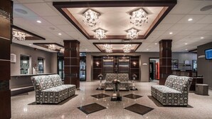 A lobby with patterned sofas, a central table, and chandeliers. - West Wing at Park Town (Saskatoon)