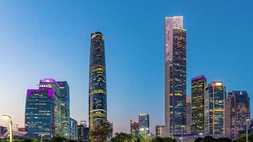 A cityscape with modern skyscrapers, including a tall cylindrical building and a rectangular skyscraper with illuminated windows.