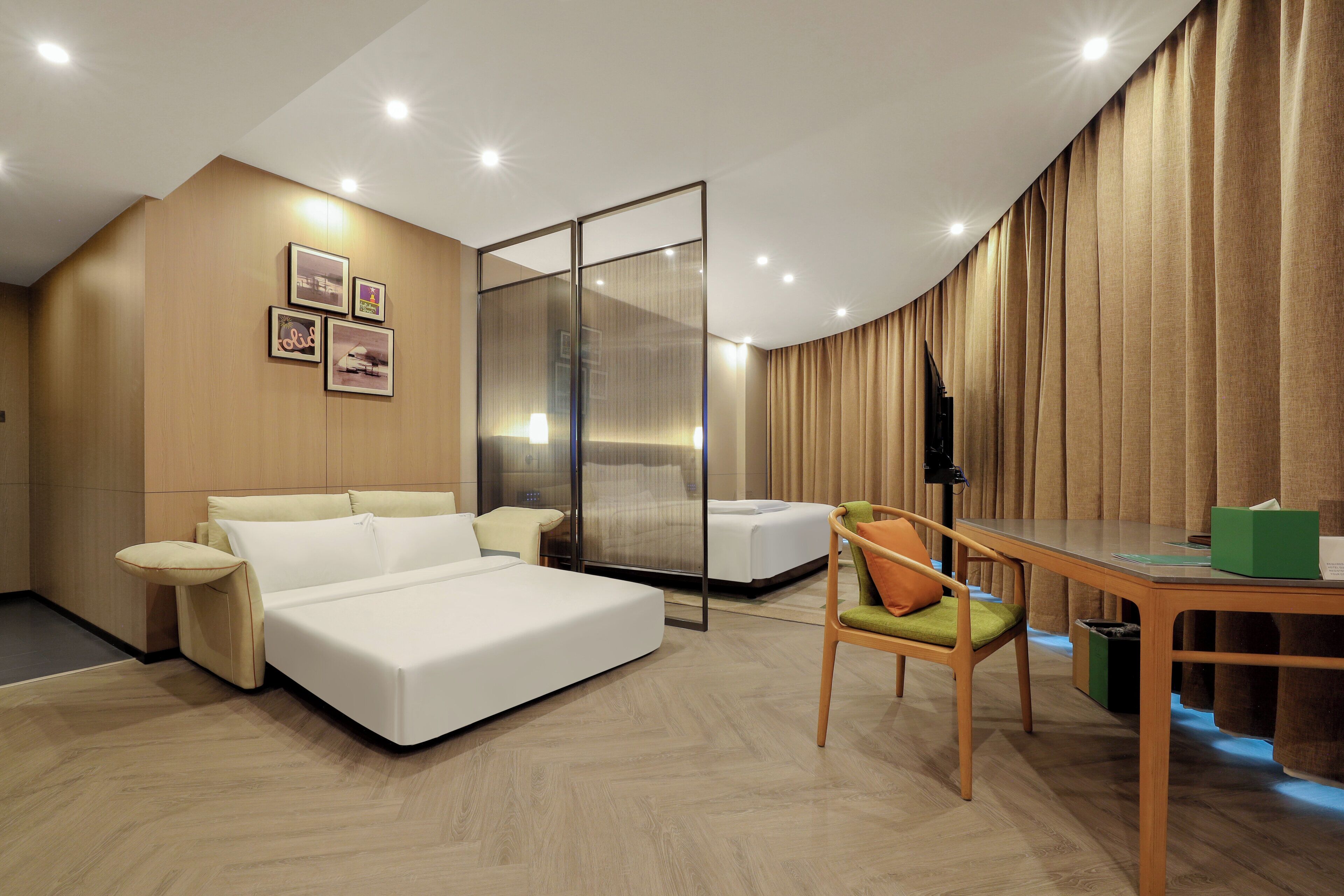 Quarto de hotel moderno com cama, escrivaninha, cadeira e uma grande janela.