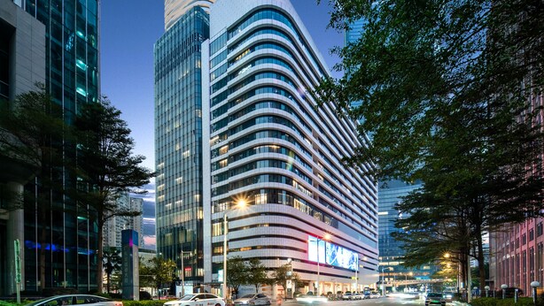 Un hotel moderno con fachada curva, amplias ventanas y un letrero llamativo.