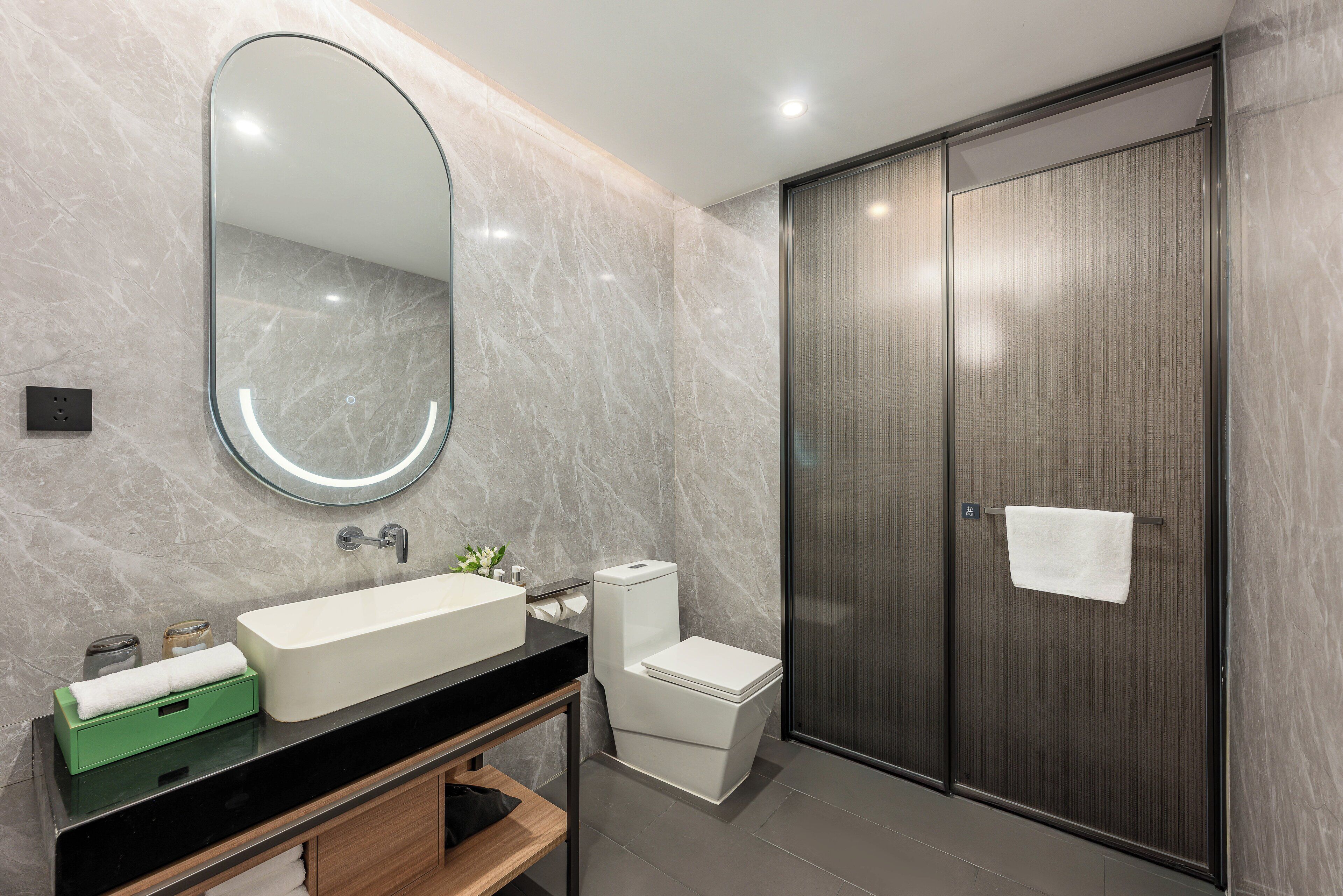 A modern bathroom with a large mirror, a sink, a toilet, and a shower enclosure.