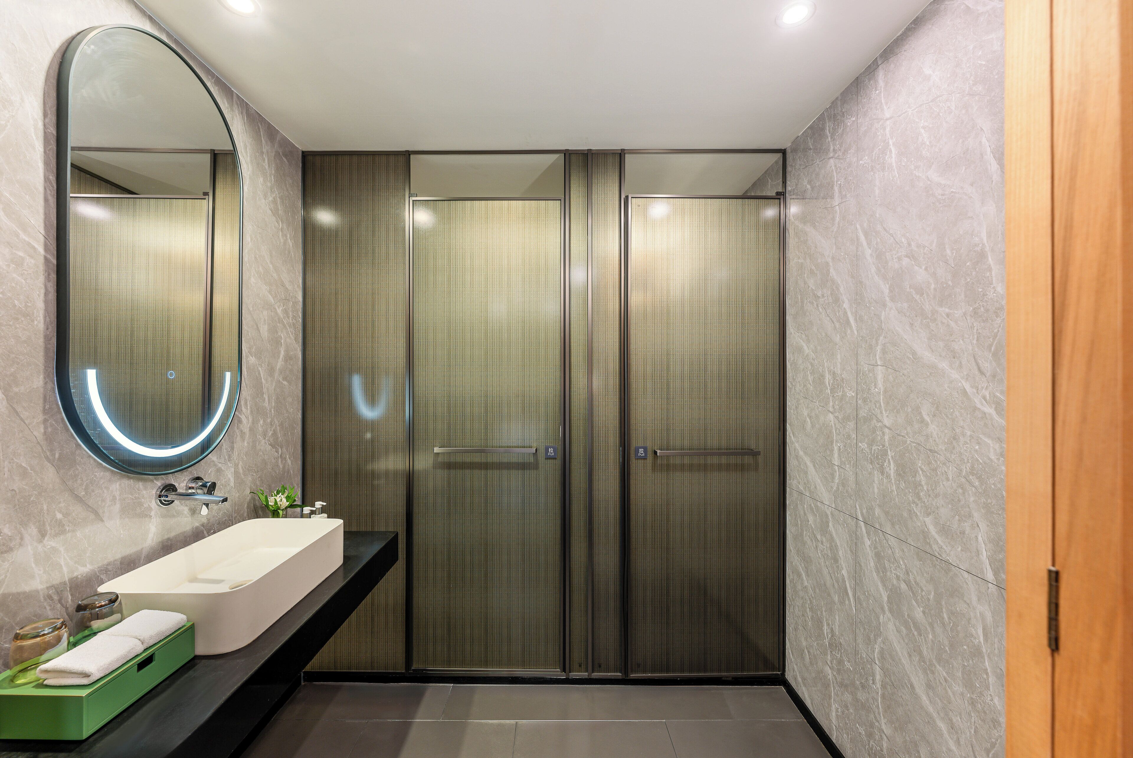 A modern bathroom with a large mirror, a white sink, and a green storage unit.