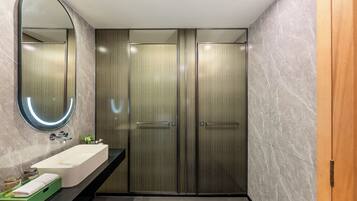 A modern bathroom with a large mirror, a white sink, and a green storage unit.
