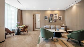 A modern hotel lobby with a seating area, a reception desk, and a wall adorned with framed artwork.