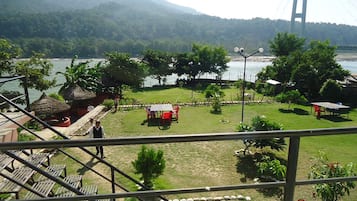 Vista de un hotel con comedor, mesas al aire libre y vistas a un puente y montañas.