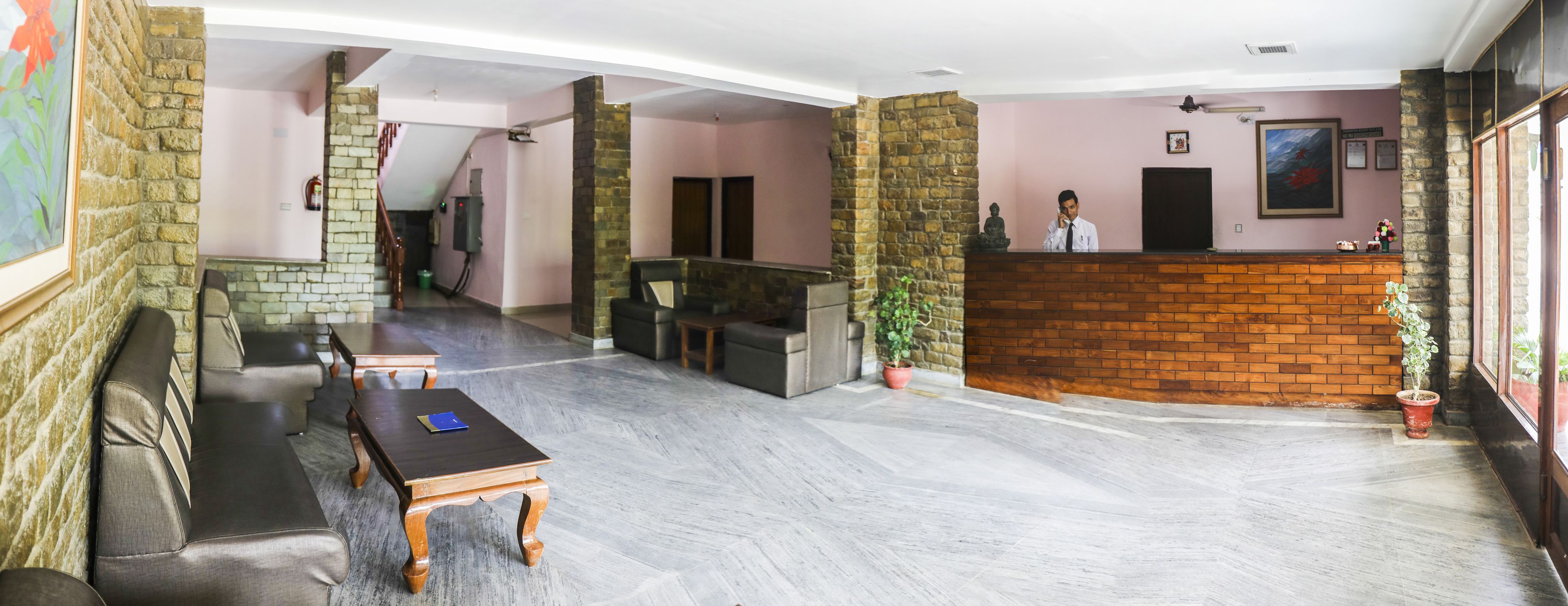 A hotel lobby with a reception desk, seating area, and a staircase leading to an upper floor.