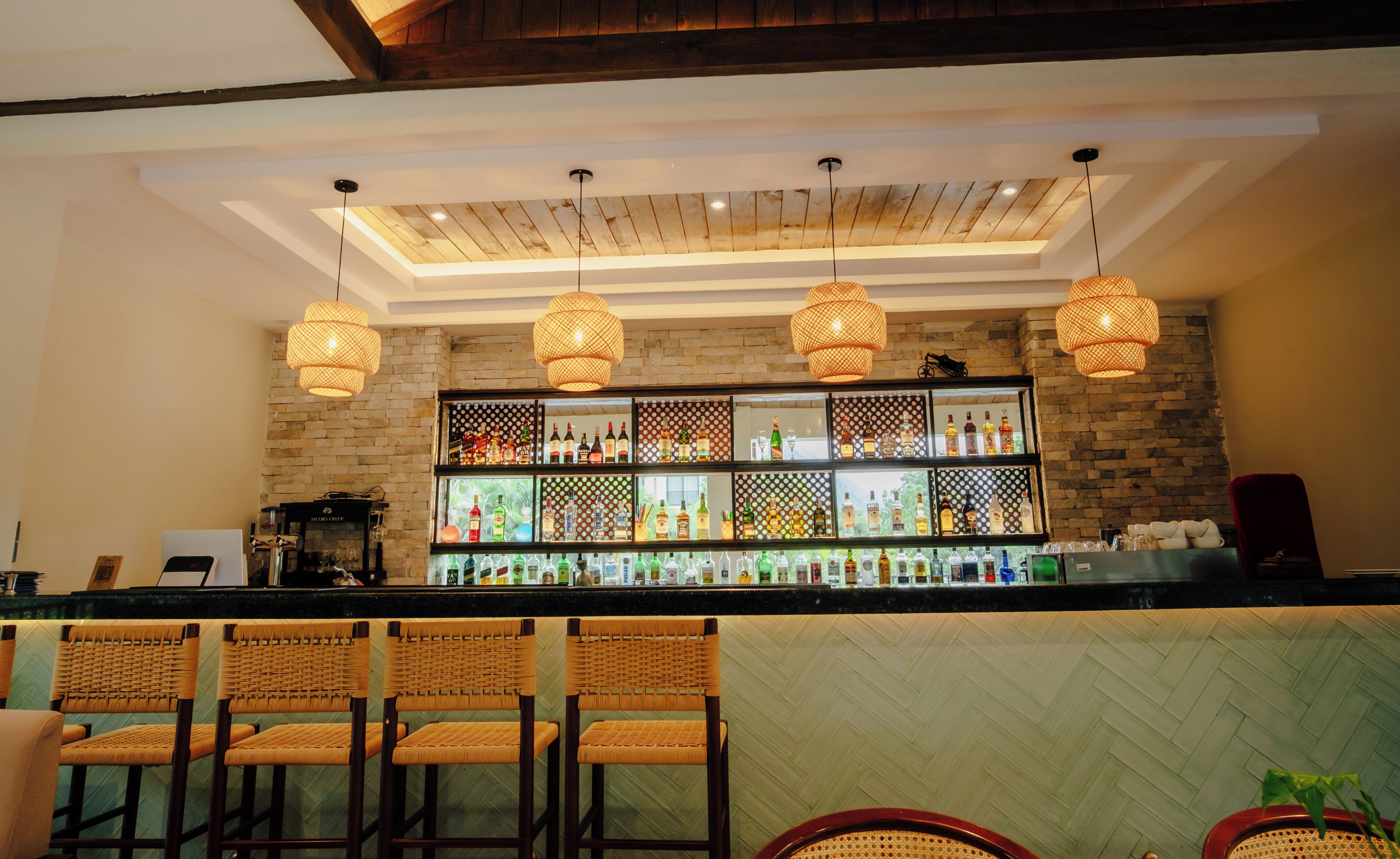 Un rincón bar con sillas de mimbre, techo de madera y pared de ladrillo.