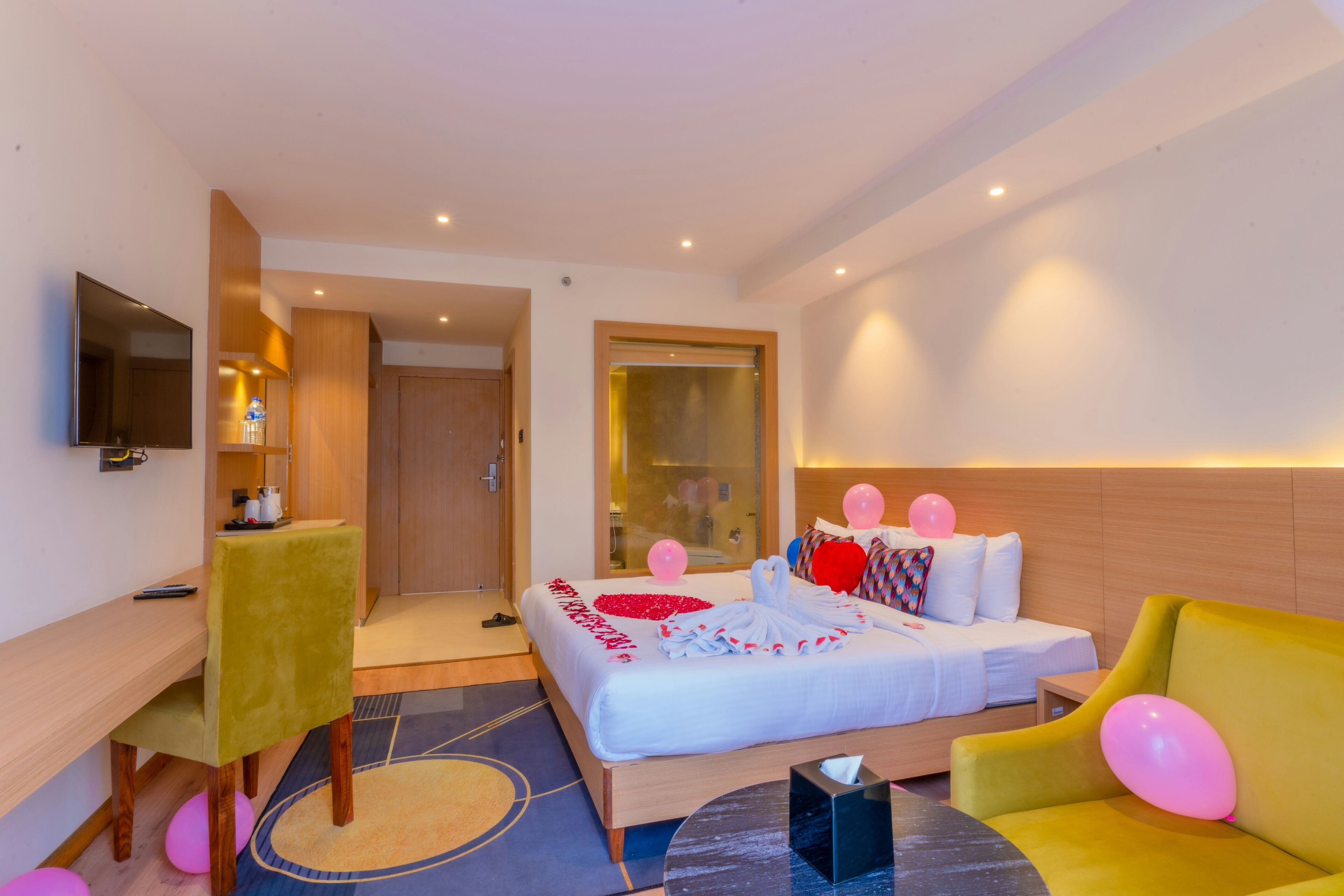 A hotel room with a bed, a desk, a chair, a sofa, and a television.