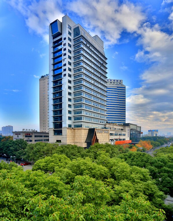 A modern high-rise building with multiple floors, large windows, and a prominent entrance. - Yiwu Bali Plaza Hotel (Jinhua)