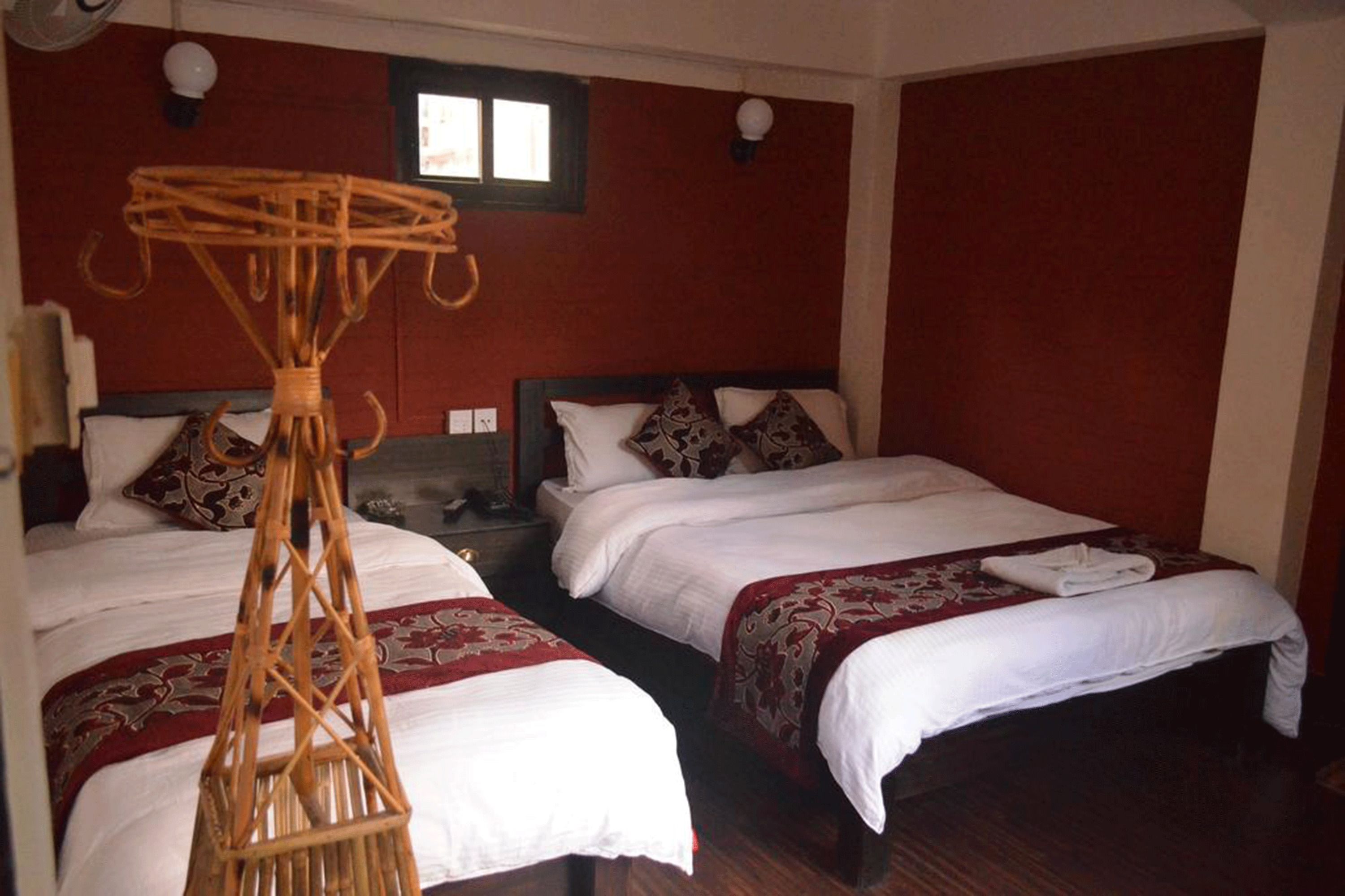 A hotel room with two beds, a wooden bed frame, and a woven headboard.