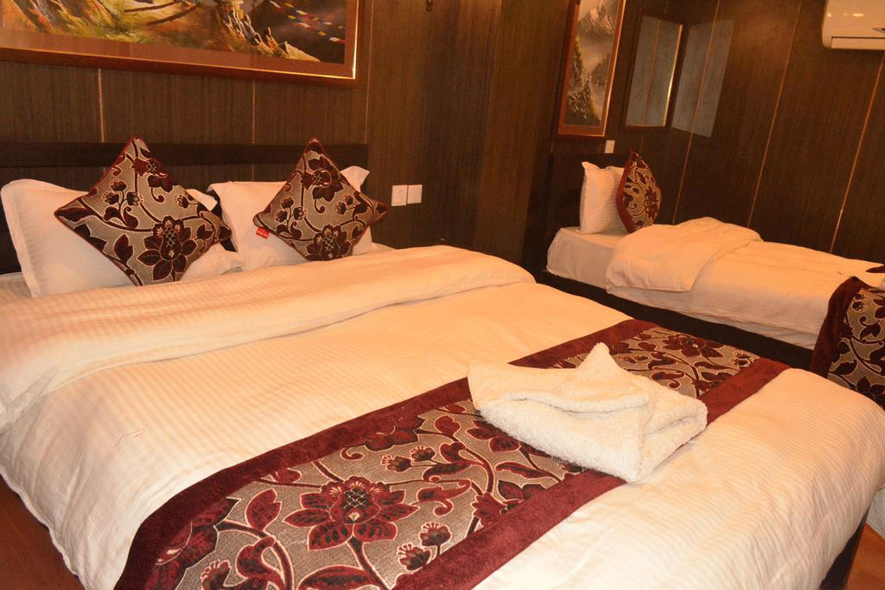 A hotel room with two beds, each with a floral-patterned bedspread and matching pillows.