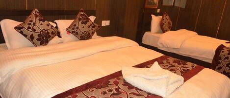A hotel room with two beds, each with a floral-patterned bedspread and matching pillows.