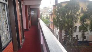 A narrow corridor with a red carpet, metal gates, and a view of neighboring buildings. - Hotel holiday inn (Kathmandu)