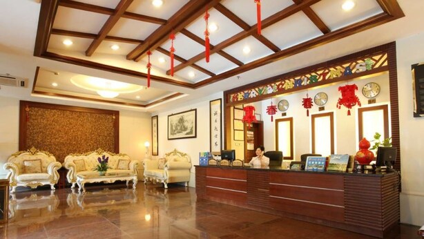 A hotel reception area with a wooden reception desk, two sofas, and a chandelier. - Guangzhou Conghua Yincheng Hotel (Guangzhou)