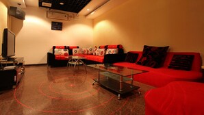 A modern living room with a red sofa, a glass coffee table, and a television on a stand. - Guangzhou Conghua Yincheng Hotel (Guangzhou)