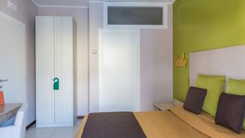 A bedroom with a bed, a wardrobe, a desk, and a green wall with a 'Smile' sign.