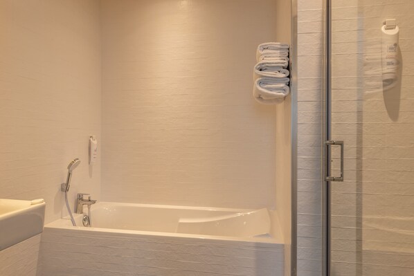Une salle de bain moderne équipée d’une baignoire, d’une douche et d’un espace de douche séparé par des parois en verre.
