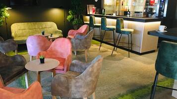 Un espace salon confortable avec des fauteuils moelleux, un bar et un écran de télévision.