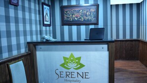 Ein Empfangstresen mit dem Logo von 'Serene Hospitality' und einem darauf liegenden Laptop.