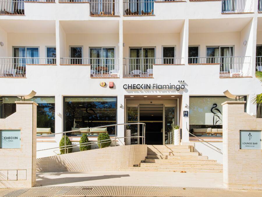 Entrada de un hotel con una escalera que lleva a la puerta, un cartel que indica Checkin Flamingo hotel y un letrero de bar lounge.