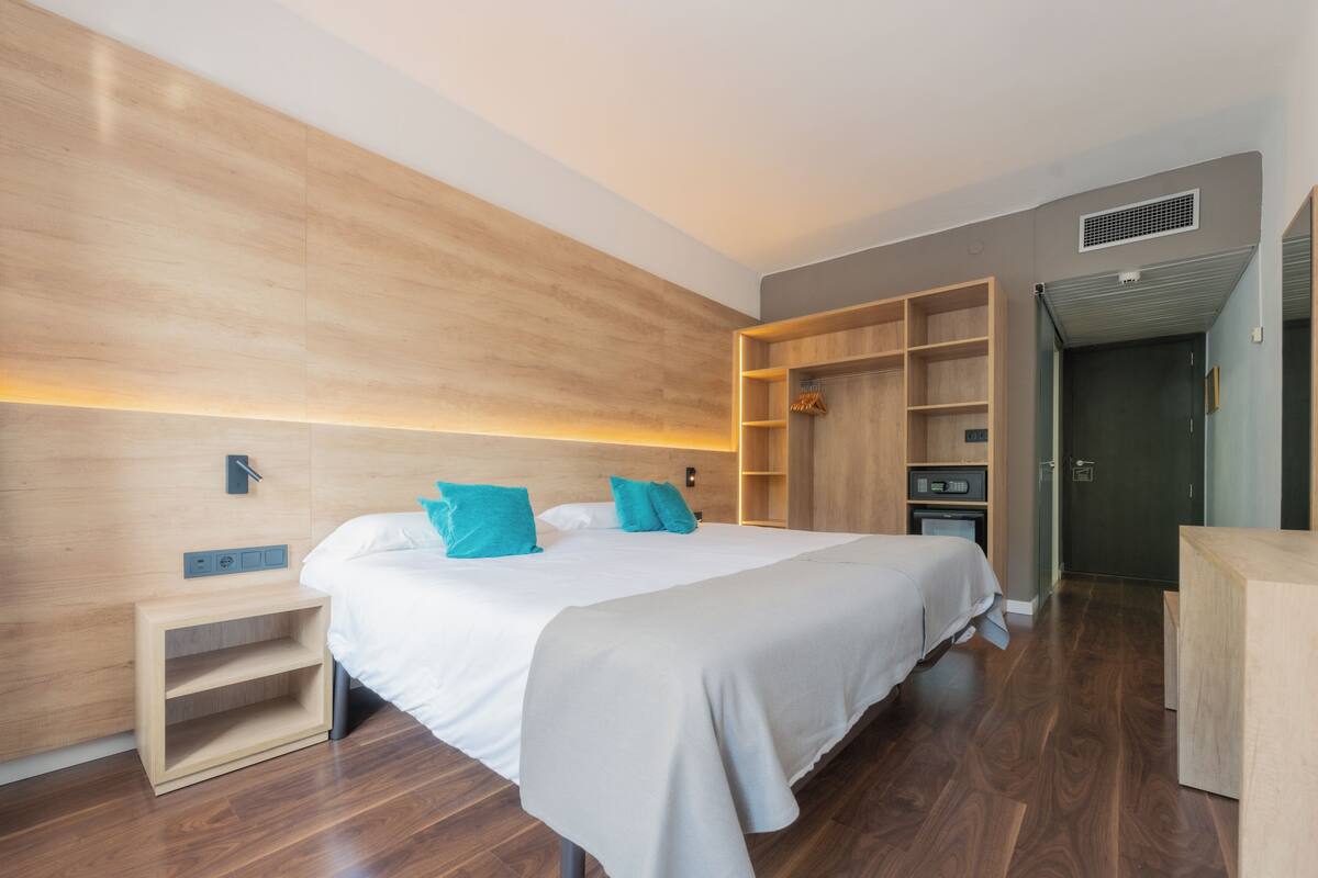 A modern hotel room with a large bed, built-in shelving, and a small desk.