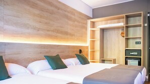 Habitación de hotel con dos camas, cabecero de madera, armario empotrado y minibar.