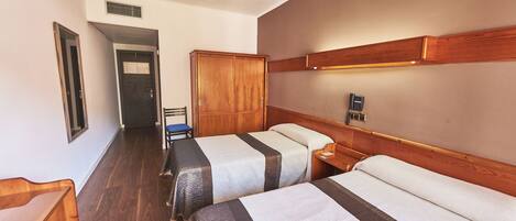 Ein Hotelzimmer mit zwei Betten, einem Holzschrank, einem Schreibtisch und einem Stuhl.