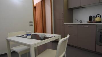 A compact kitchen with a dining area, featuring a white table, chairs, and a built-in oven.