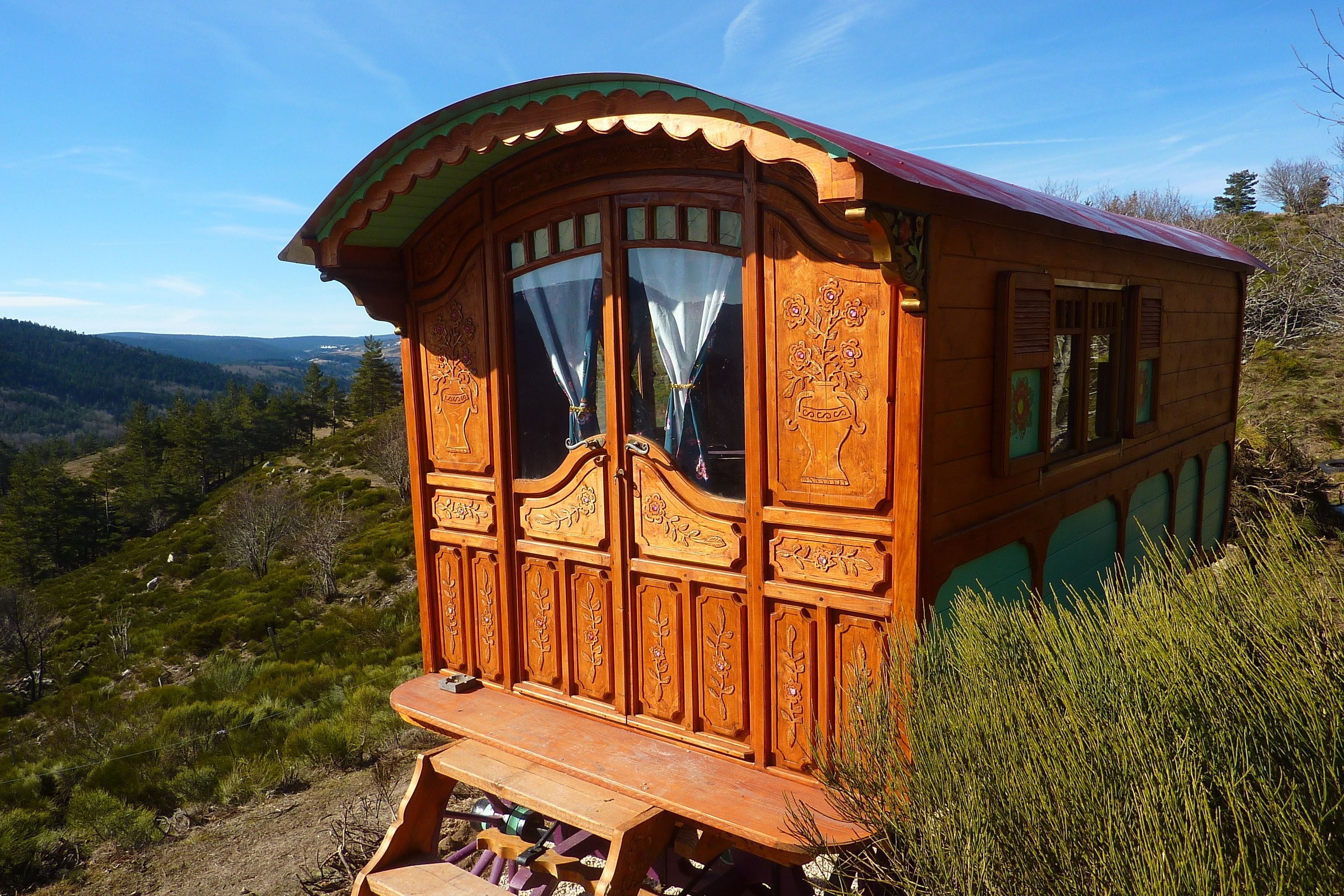 Una cabaña de madera con delicados grabados, un banco y una vista panorámica del paisaje circundante.