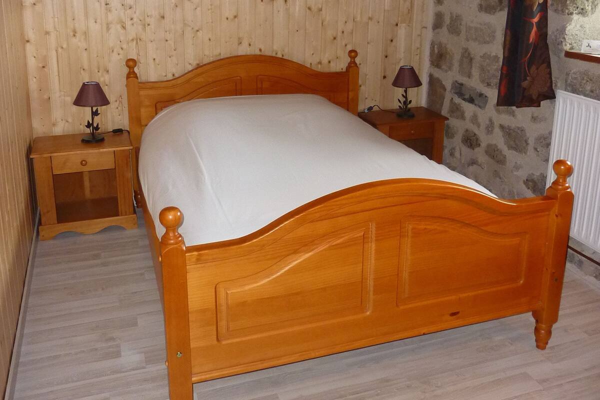 A wooden bed in a room with wooden walls and a stone wall.