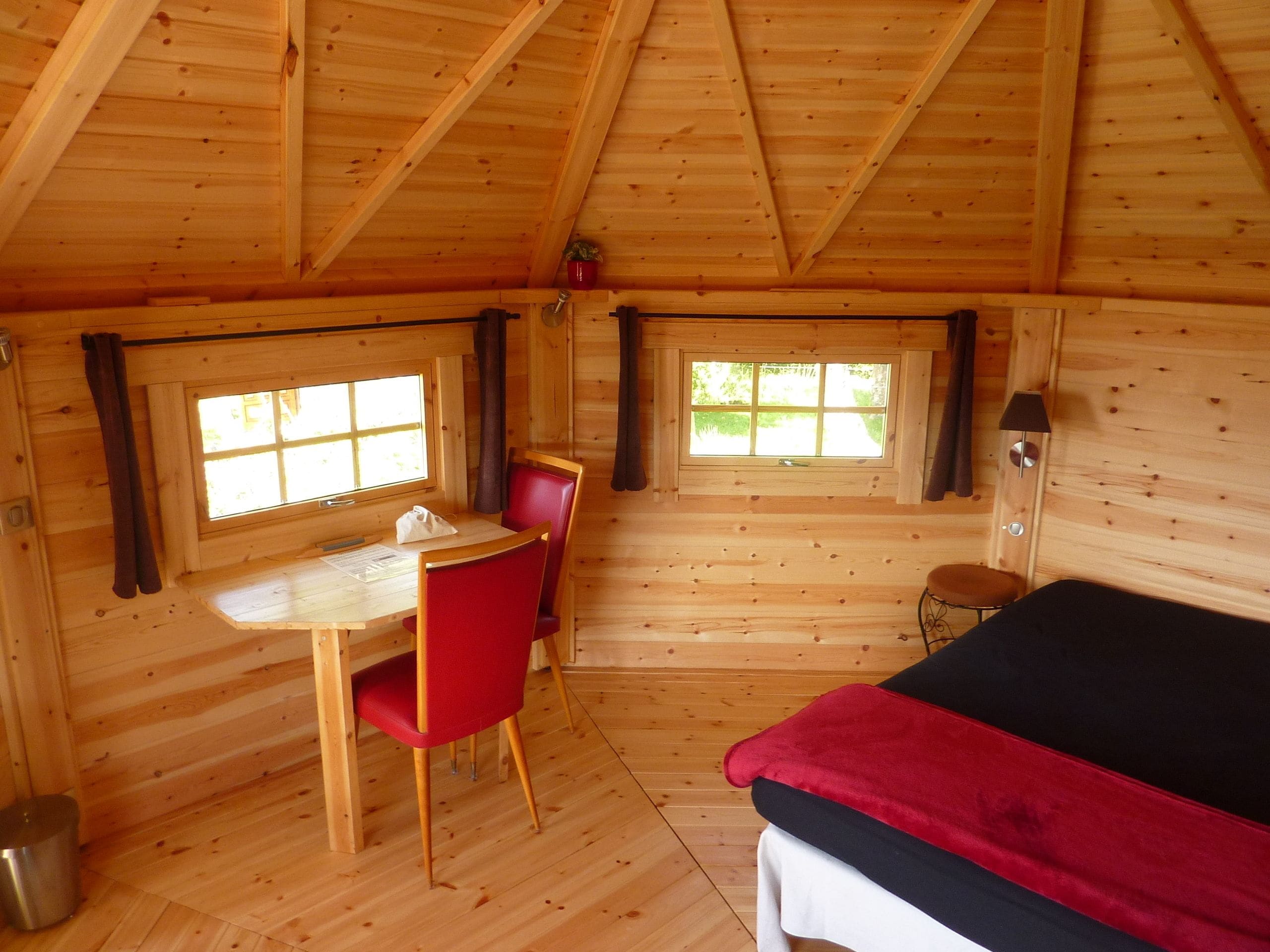 A wooden cabin room with a bed, a table, and two chairs.