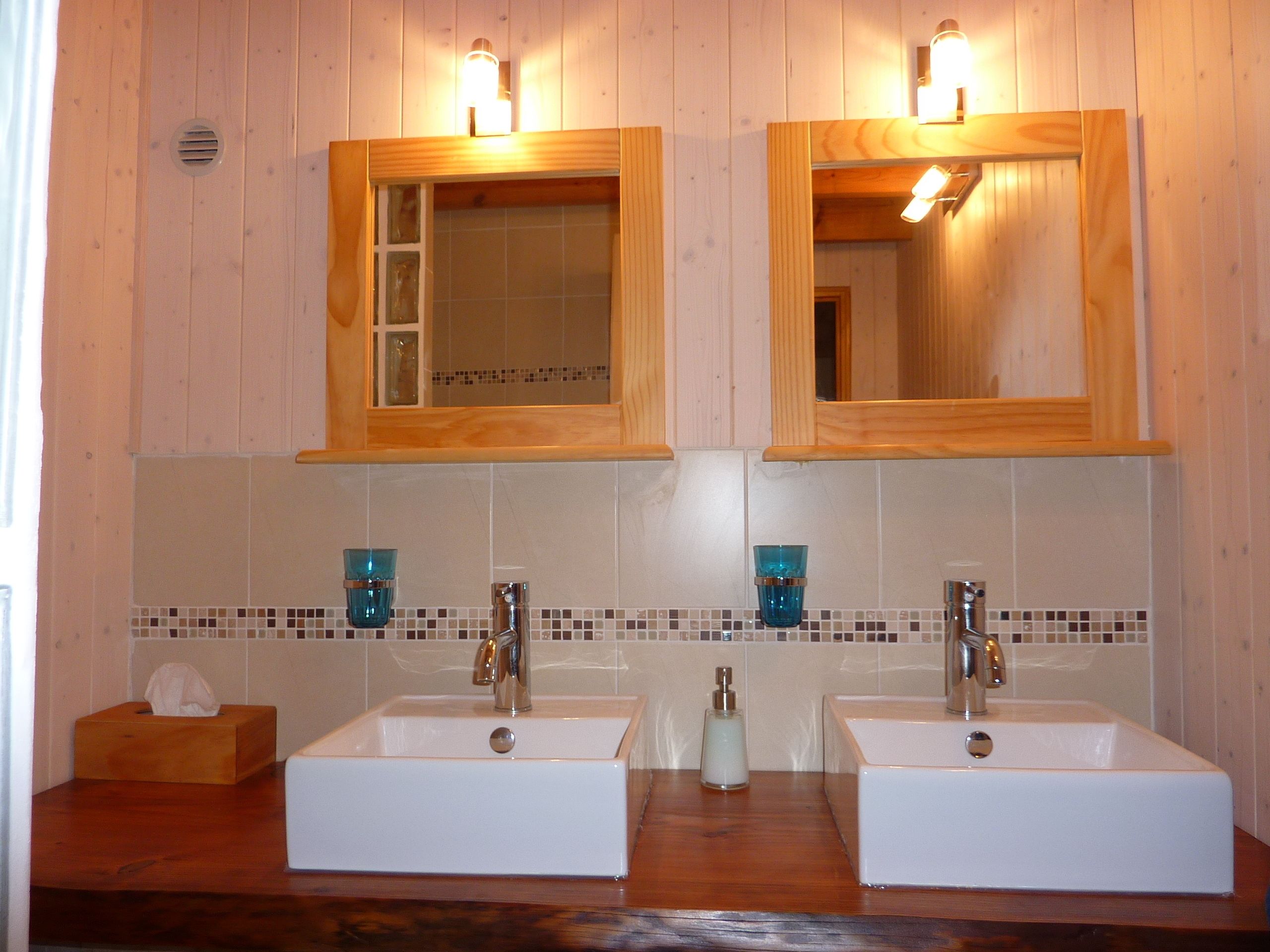 A bathroom with two sinks, wooden cabinets, and mirrored medicine cabinets.