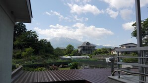 A view of a residential area with a mountain in the background, a pond, and a building under construction. - Yagisakien (Fujikawaguchiko)
