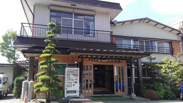 A two-story building with a wooden facade, a balcony on the upper floor, and a small entrance with a wooden sign. - Yagisakien (Fujikawaguchiko)