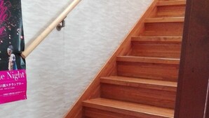 A wooden staircase with a handrail and a poster on the wall. - Yagisakien (Fujikawaguchiko)