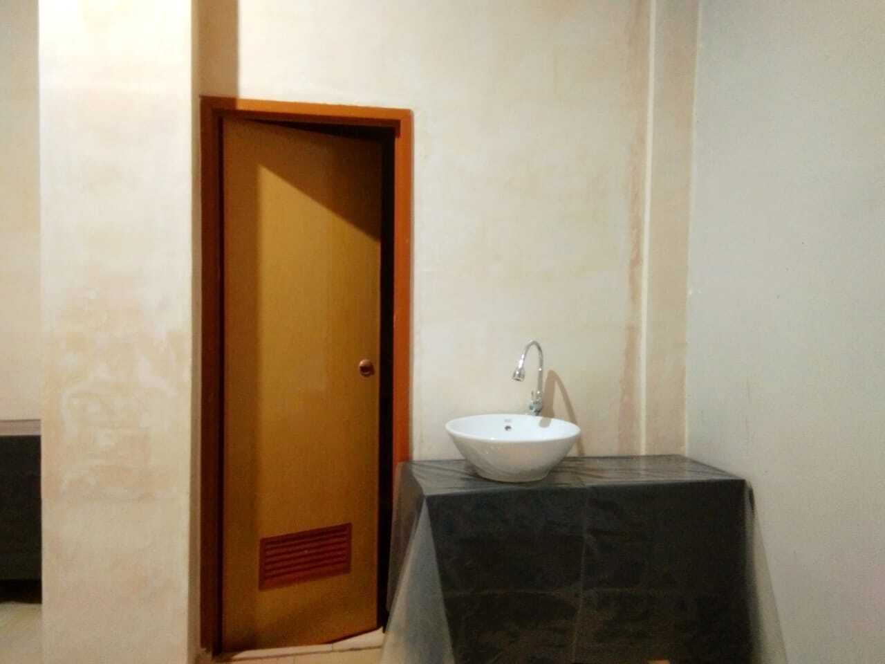 A bathroom with a wooden door, a white sink, and a marble countertop.